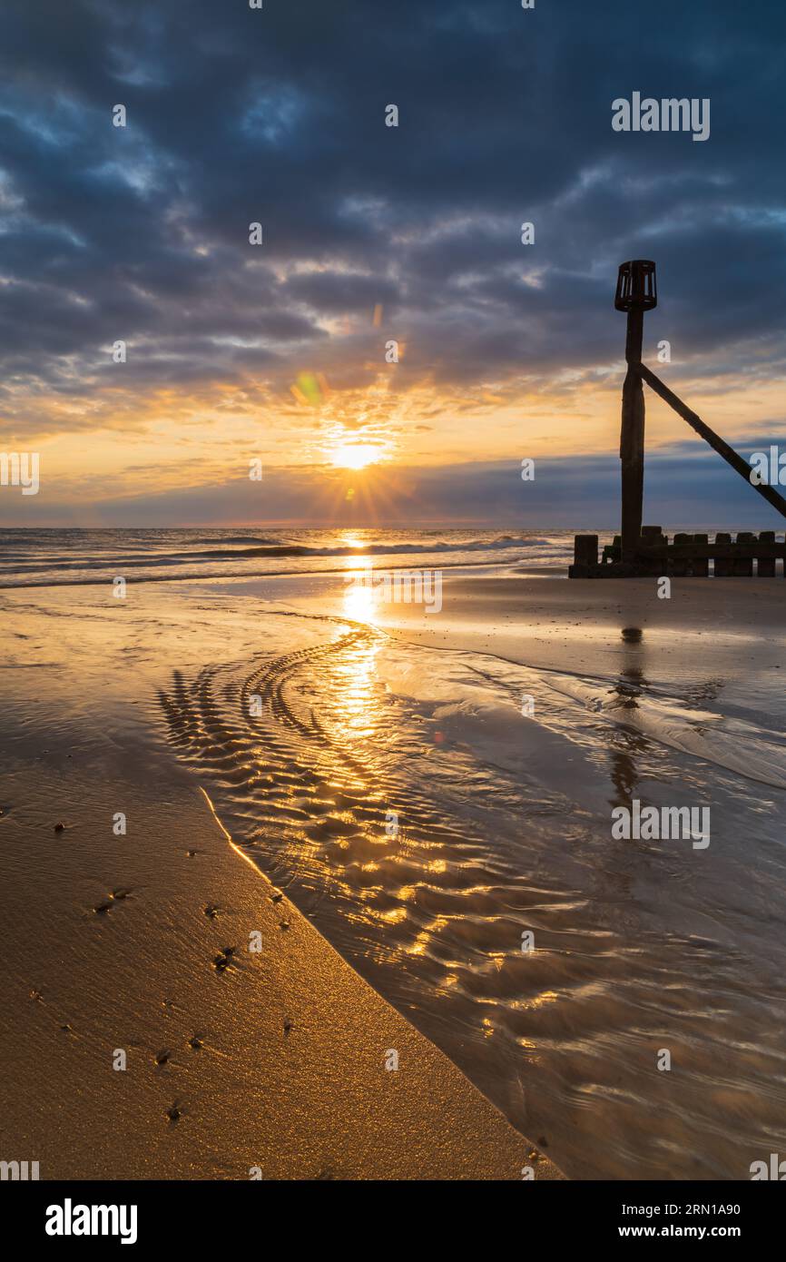 A portrait image of the sunrise on the beach in Mundesley, North Norfolk, UK Stock Photo