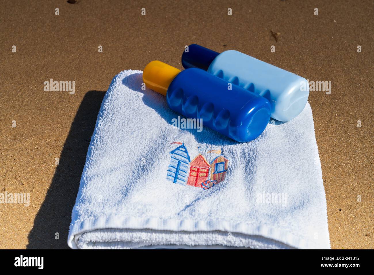 Beach towel and suntan spray bottles on the beach.  Summer holiday/vacation concept Stock Photo