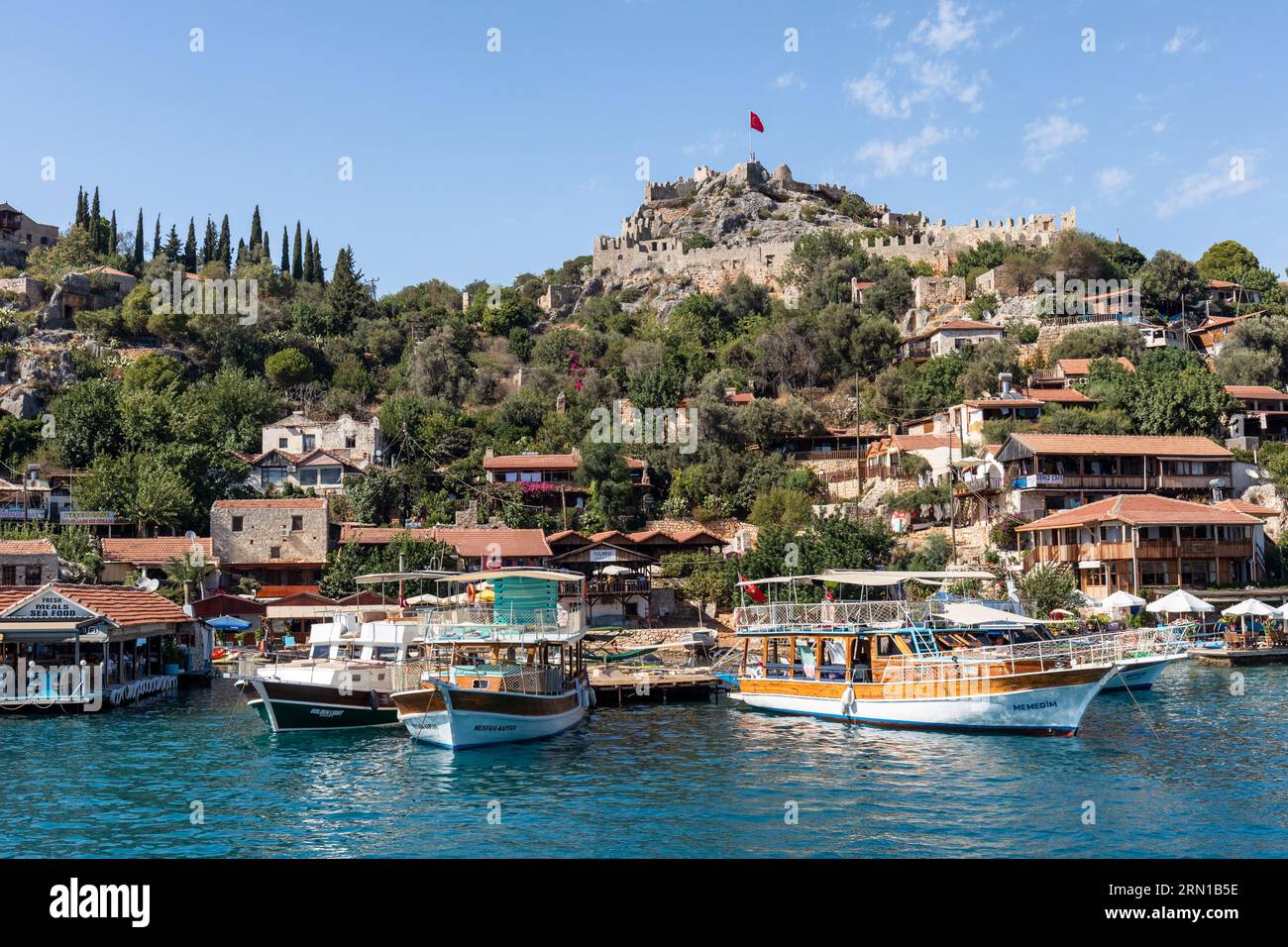 Simena village and castle as seen from an arriving tourist tour boat , Simena, Kalekoy, Turkey Stock Photo