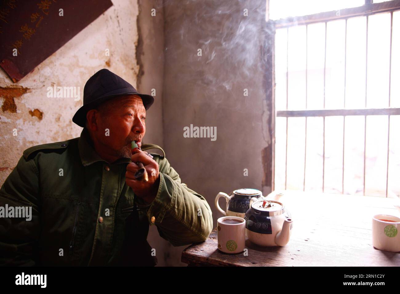 An elder smokes pipe in an old tea house in Linhuan Town, Suixi County of Huaibei City, east Chin s Anhui Province, Dec. 11, 2014. Linhuan Town, located in the southwest of Suixi County of Huaibei City in east China s Anhui Province, has a long history that can dates back to more than four thousand years ago. Local people of Linhuan has kept the tradition of drinking tea since Ming Dynasty, which leaves its print on people s life here through the old square table, the rough sand bowl and the rusty copper tea pot. Customers usually show up at the tea house at ten in the morning, where they can Stock Photo