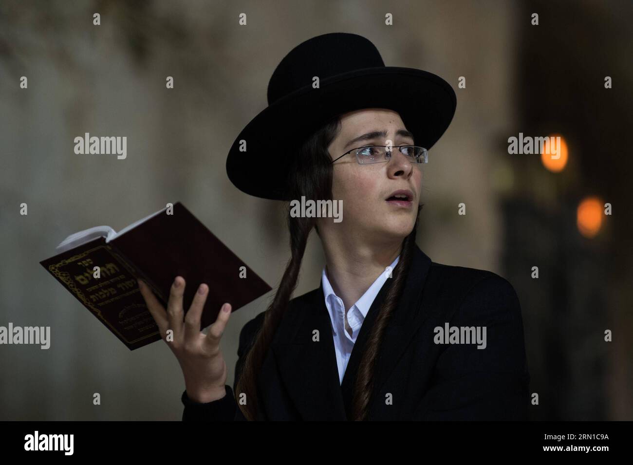 JERUSALEM, Dec. 16, 2014 -- An Ultra-Orthodox Jewish man prays to mark Hanukkah in front of a large-sized Hannukiya at the Western Wall in the Old City of Jerusalem, on Dec. 16, 2014. Hanukkah, also known as the Festival of Lights and Feast of Dedication, is an eight-day Jewish holiday commemorating the rededication of the Holy Temple (the Second Temple) in Jerusalem at the time of the Maccabean Revolt against the Seleucid Empire of the 2nd Century B.C. Hanukkah is observed for eight nights and days, starting on the 25th day of Kislev according to the Hebrew calendar, which may occur at any ti Stock Photo