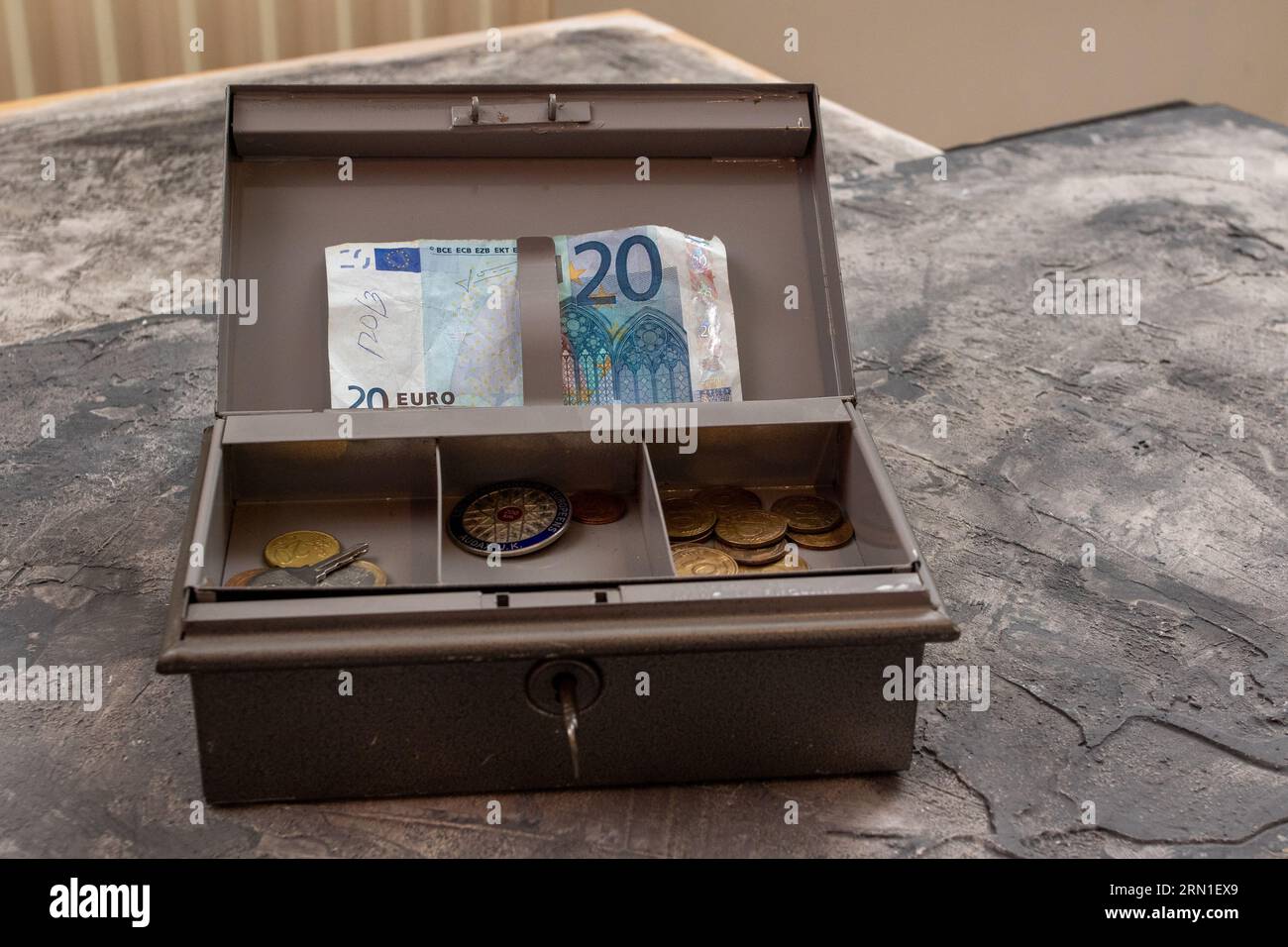 Grey metal petty cashbox containing a 20 Euro banknote and coins in a tray Stock Photo