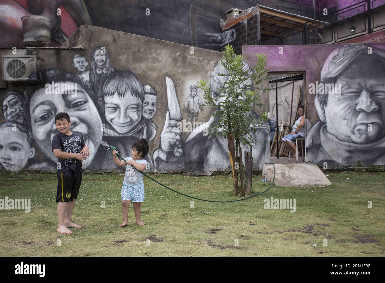 BUENOS AIRES, Dec. 27, 2014 -- Children play with water in front of the mural El Regreso de Quinquela , created by Argentine artist and urban muralist Alfredo Segatori, in Buenos Aires, Argentina, on Dec. 27, 2014. Made on a surface of over 2,000 square meters, the mural became on Saturday the largest in the world, according to local press. Martin Zabala)(zhf) ARGENTINA-BUENOS AIRES-CULTURE-MURAL e MARTINxZABALA PUBLICATIONxNOTxINxCHN   Buenos Aires DEC 27 2014 Children Play With Water in Front of The Mural El Regreso de  Created by Argentine Artist and Urban muralist Alfredo  in Buenos Aires Stock Photo