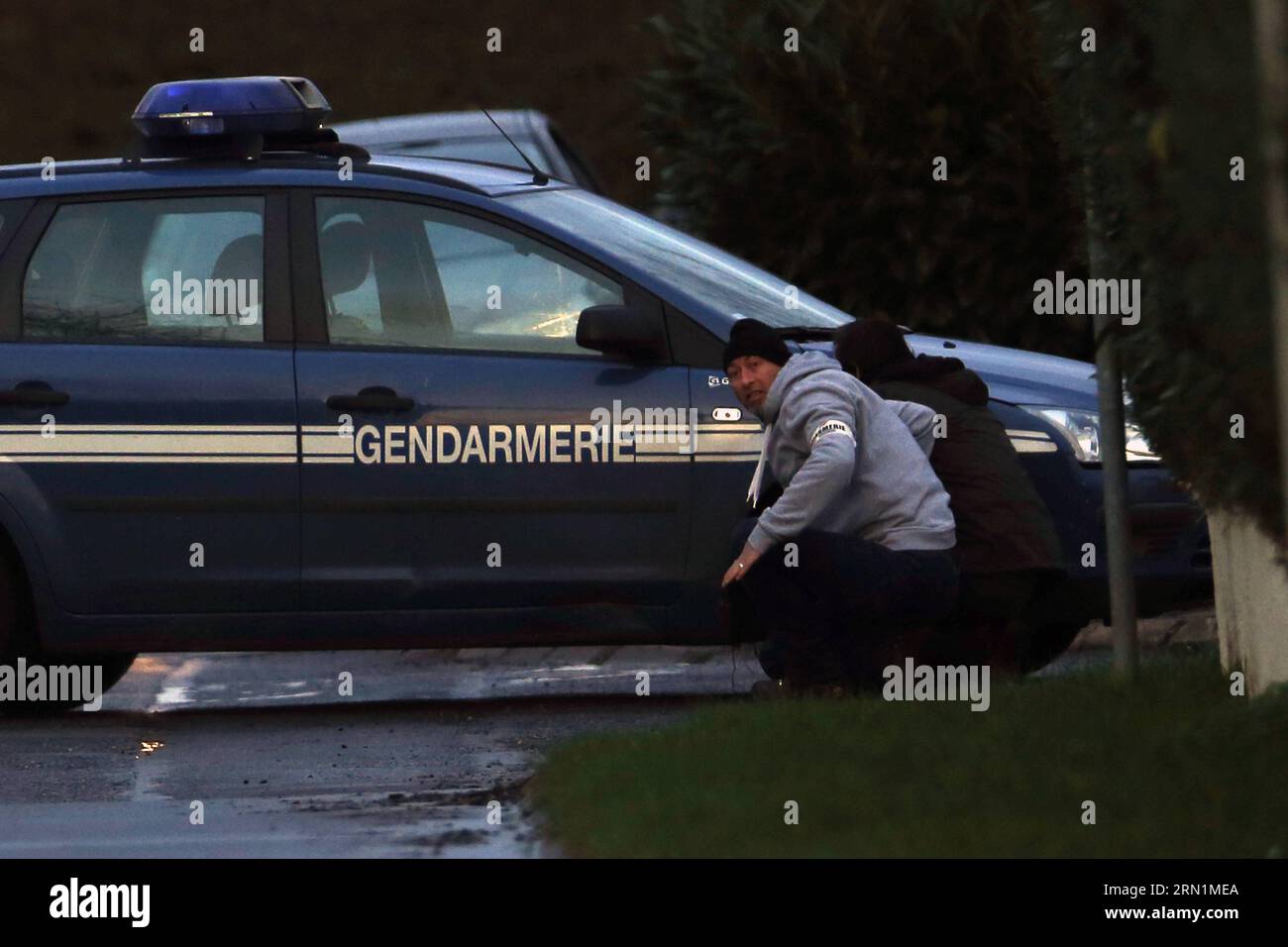 Two plainclothes hide behind a police car in Dammartin-en-Goele, northeast of Paris, where two brothers suspected of Charlie Hebdo attack held one person hostage as police cornered the gunmen, on Jan. 9, 2015. The Kouachi brothers, suspects of Charlie Hebdo attacks, were killed during French security force s assault on Friday evening, and the hostages are alive. ) FRANCE-DAMMARTIN-EN-GOELE-CHARLIE-SUSPECTS-ASSAULT-OPERATION RaoulxChombier PUBLICATIONxNOTxINxCHN   Two plainclothes HIDE behind a Police Car in  en  Northeast of Paris Where Two Brothers suspected of Charlie Hebdo Attack Hero One P Stock Photo