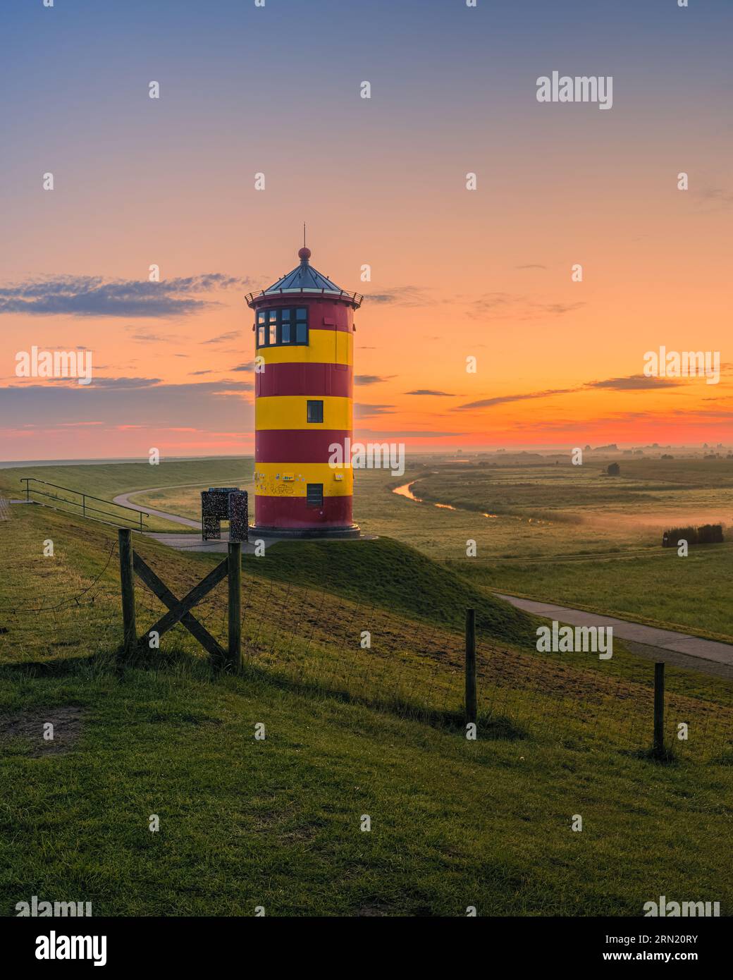 A vertical 4:5 image of a sunrise at the lighthouse of Pilsum, located between Pilsum and Greetsiel on the North Sea dike that belongs to the municipa Stock Photo