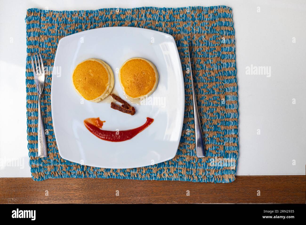 Top view of fork and knife next to breakfast plate on dining table On