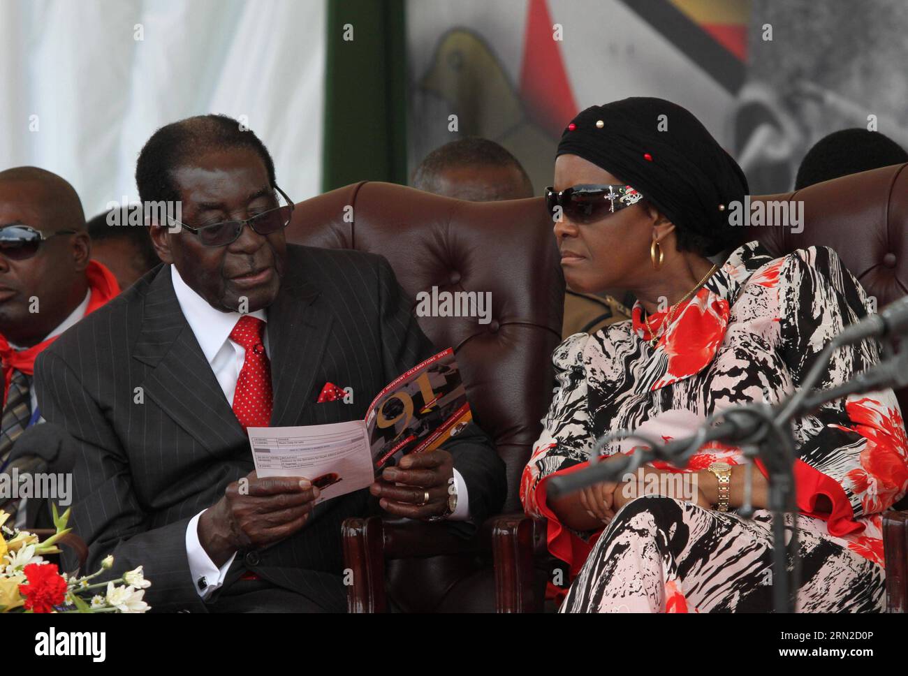 (150228) -- VICTORIA FALLS (ZIMBABWE), Feb. 28, 2015 () -- Zimbabwean President Robert Mugabe (L) and his wife Grace Mugabe browse a brochure on the podium at a public celebration held to mark his 91st birthday in Victoria Falls, Zimbabwe, Feb. 28, 2015. Mugabe, who turns 91 this month, is the oldest leader in the world and one of the longest-serving African statesmen. Having ruled Zimbabwe for 35 years since independence, Mugabe was endorsed by the ruling ZANU-PF party as the sole candidate to contest at the age of 94 in the next presidential election in 2018. () ZIMBABWE-VICTORIA FALLS-MUGAB Stock Photo