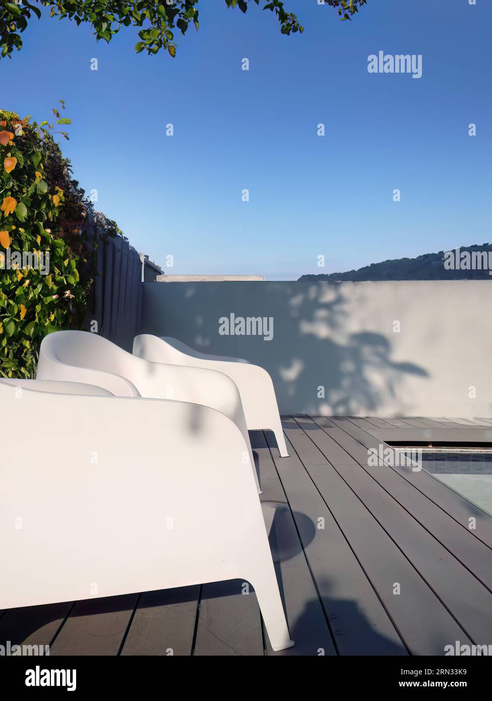 Modern design white plastic chairs at swimming pool side and outdoor garden, comfortable veranda decorated, wooden deck, back yard privacy space for r Stock Photo