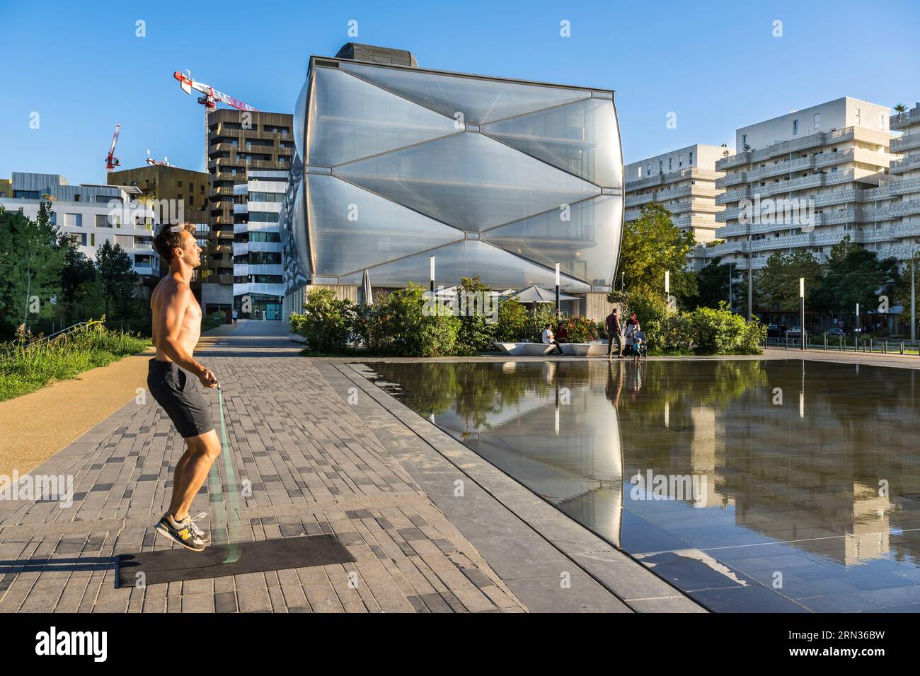 France, Herault, Montpellier, Port Marianne district, Le Nuage building by designer Philippe Starck, sportsman jumping rope in front of the water mirror in the foreground on avenue Raymond Dugrand Stock Photo