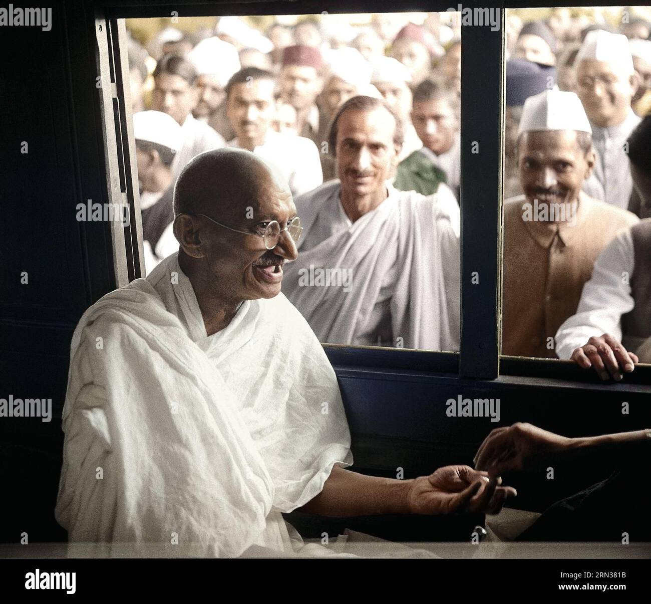 Mahatma Gandhi receives a donation in a train compartment. Acharya Kripalani and Radhakrishna Bajaj are looking through the window, 1940. Stock Photo