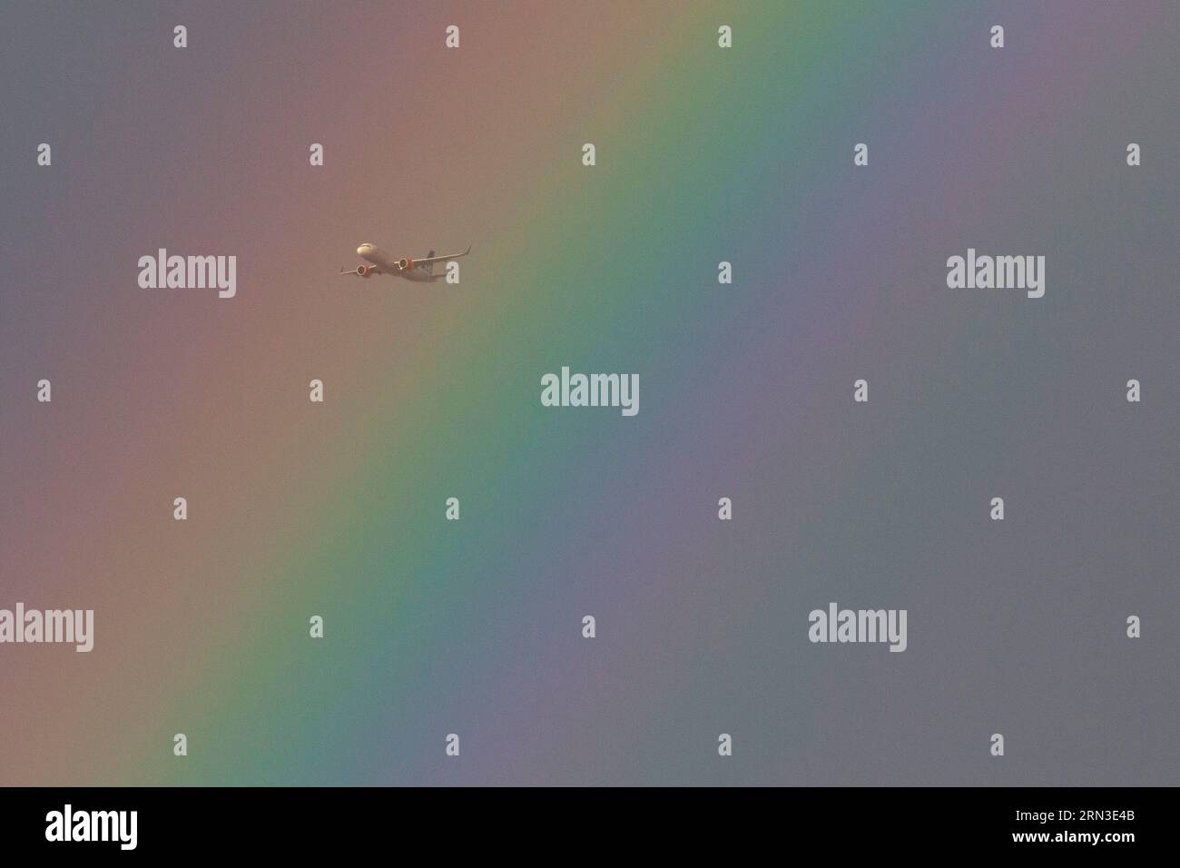London, UK, 26 August 2023: An aeroplane passes through a rainbow above south London. Anna Watson/Alamy Stock Photo