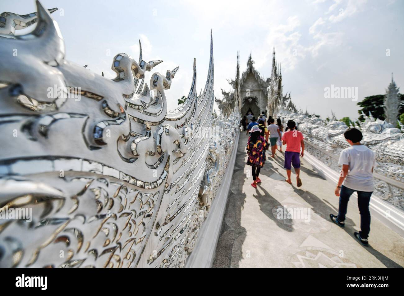 (150418) -- CHIANG RAI, April 17, 2015 -- Tourists pass the bridge of the cycle of rebirth on their way to the Ubosot hall of Wat Rong Khun in Chiang Rai, Thailand, April 17, 2015. Wat Rong Khun, commonly known as the White Temple, is a buddhist temple designed and owned by Thai artist Chalermchai Kositpipat. Featuring white architectural structures adorned with silvery reflective foils as well as decorative contemporary paintings, Wat Rong Khun serves as a popular tourist destination in Chiang Rai. )(azp) THAILAND-CHIANG RAI-WAT RONG KHUN-WHITE TEMPLE LixMangmang PUBLICATIONxNOTxINxCHN   Chia Stock Photo