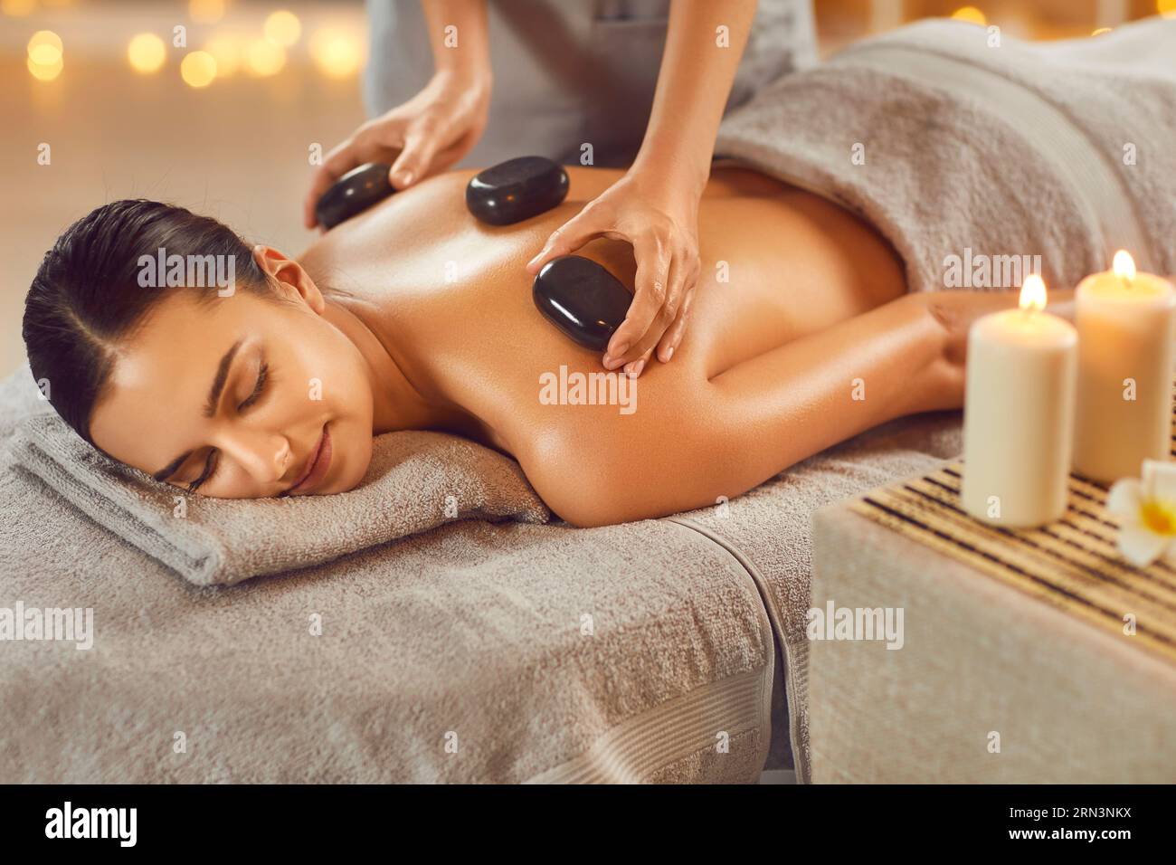 Beautiful woman enjoying massage with hot basalt stones in spa salon Stock Photo