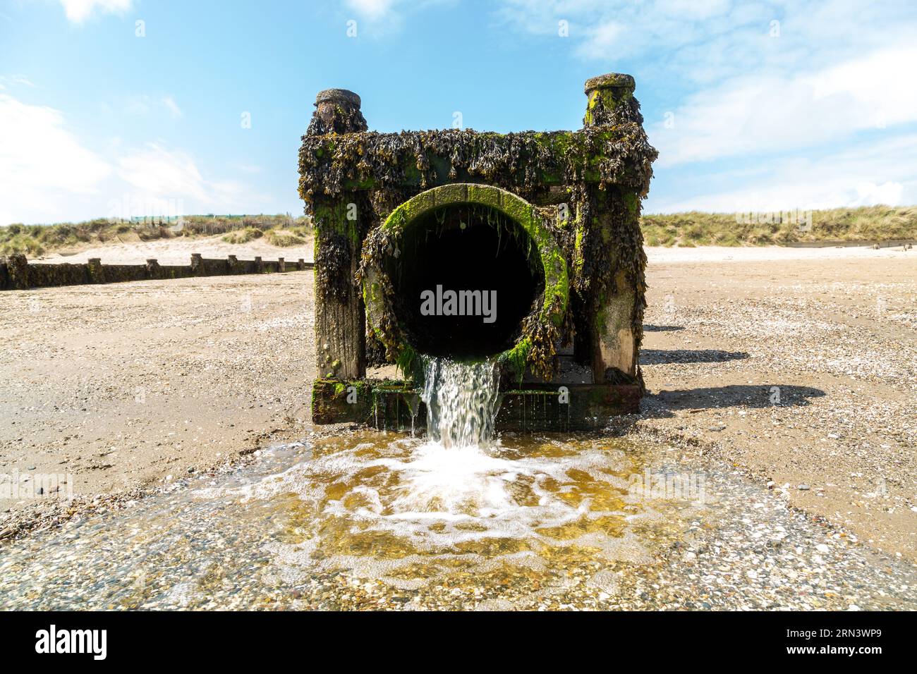 A waste water pipe with water discharging onto Abersoch beach, Wales Stock Photo