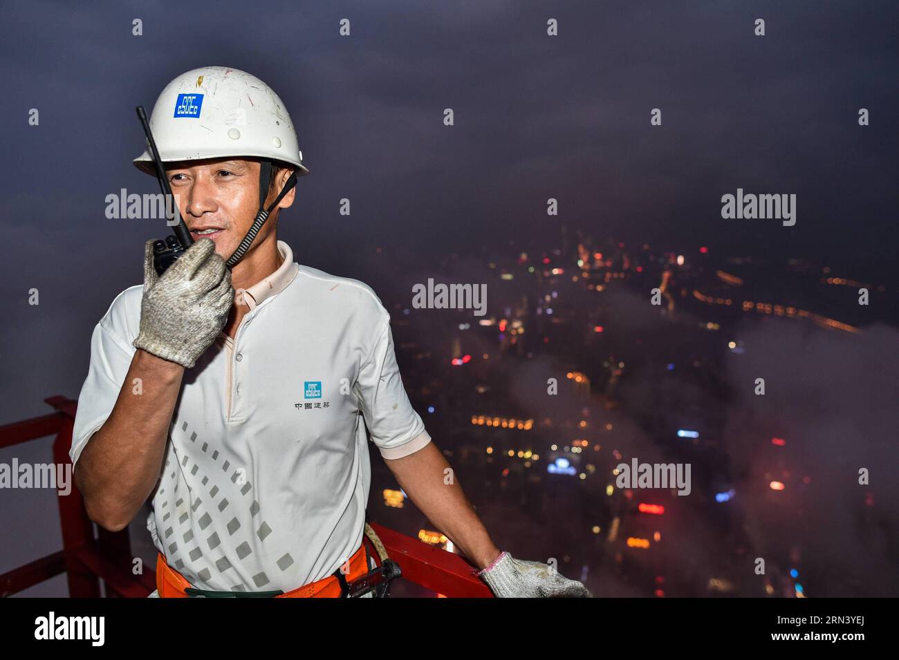 (150430) -- SHENZHEN, April 30, 2015 -- Photo taken on April 18, 2015 shows Wang Hua, a tower crane operator, communicates with signalman through a walkie talkie on a tower crane in Shenzhen, south China s Guangdong Province. Wang Hua, a 50-year-old from central China s Henan Province, is a good hand in operating tower crane. Though he used to be a security guard when he was young, he quickly grew into an excellent tower crane operator due to his diligence and love of learning. He was engaged in many larger construction projects like the new site of CCTV and the Water Cube, and the current pro Stock Photo