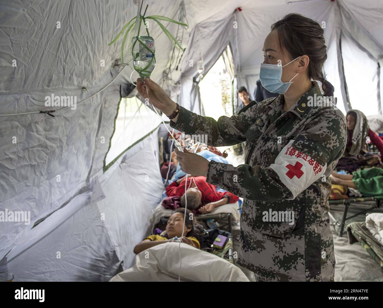 A nurse of emergency department of China s Chengdu Military Region Medical Team gives transfusion treatment for a patient in Kathmandu, Nepal, May 10, 2015. Since the arrival, the Chengdu Military Region Medical Team, the only foreign aid team capable of performing full-spectrum bone- related surgical operations, has treated over 200 patients, conducted more than 100 surgical operations, including 34 major ones. The team has also provided psychological counseling to nearly 500 people, and has disinfected a total area of over 850,000 square meters. In contrast to their typical International Nur Stock Photo