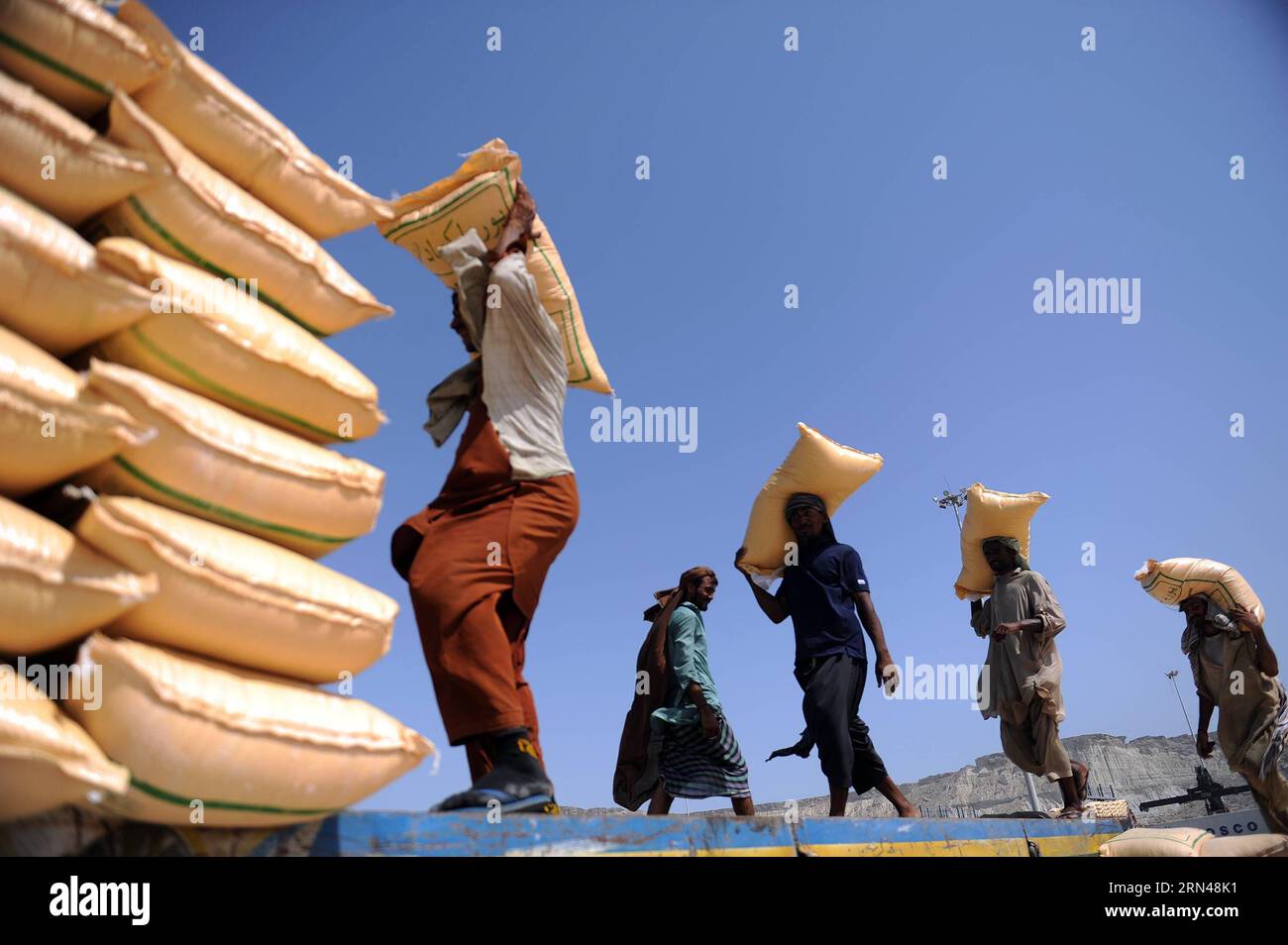 (150512) -- KARACHI,   -- Dockers carry feed bags at the pier of Gwadar Port, southwestern Pakistan, on May 11, 2015. Gwadar Port, a warm-water, deep-sea port, is located at the mouth of the Persian Gulf in Gwadar of Pakistan s Baloschistan province. China and Pakistan agreed to build China-Pakistan Economic Corridor (CPEC) to connect the Pakistani port with Kashgar city in China s Xinjiang Uygur Autonomous Region. It will shorten China s routes of oil and gas imports from Africa and the Middle East for thousands of kilometers, making Gwadar a potentially vital link in China s supply chain. Co Stock Photo