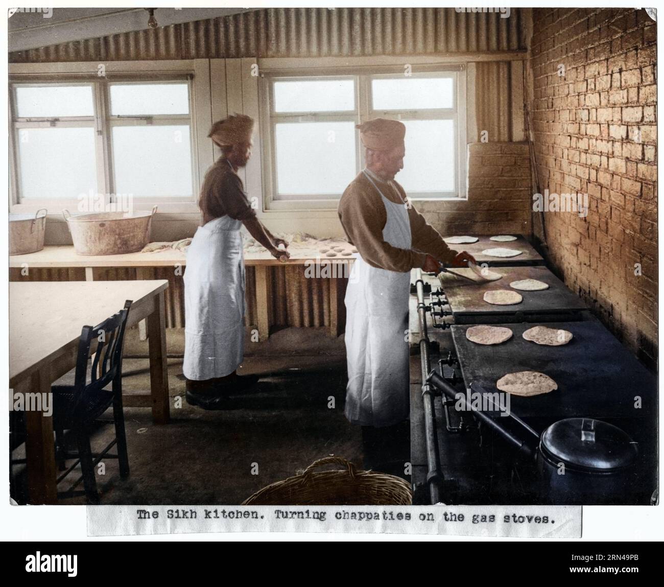 The Sikh kitchen. Turning chappaties on the gas stoves. 1915, Brighton, UK. In this photograph we can see two men cooking chapatis (an unleavened flat Stock Photo