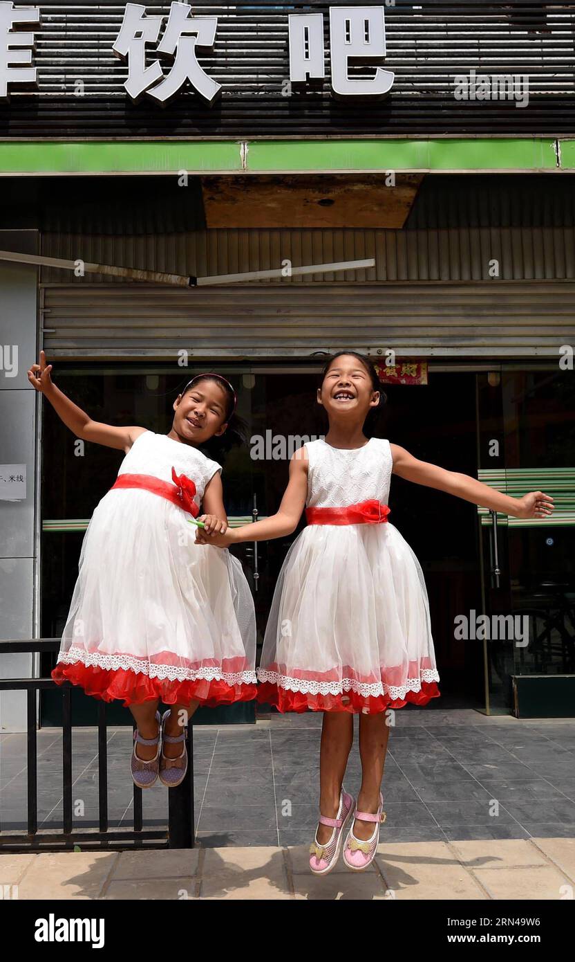 (150514) -- MOJIANG, May 12, 2015 -- Twin sisters Jin Meixian (R) and Jin Huixian play in front of the cold drink store their mother opens in Mojiang Hani Autonomous County, southwest China s Yunnan Province, May 12, 2015. Twin sisters Jin Meixian and Jin Huixian, 7, live with their mother Wang Fei, who opens a cold drink store. Their father does business in another province. Meixian, the older, loves music and wants to be a musical teacher. Huixian likes dancing, and wants to go to college in Beijing. We always feel connected. Sometimes we find out that we are singing the same song, even the Stock Photo