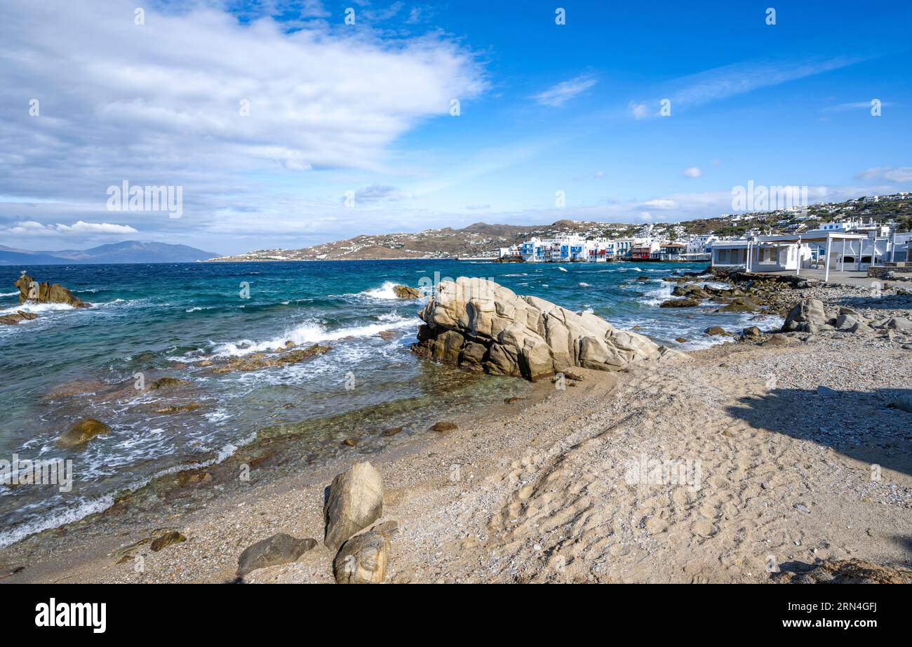 Beach with sand and rocks, white Cycladic houses in the back, Little ...