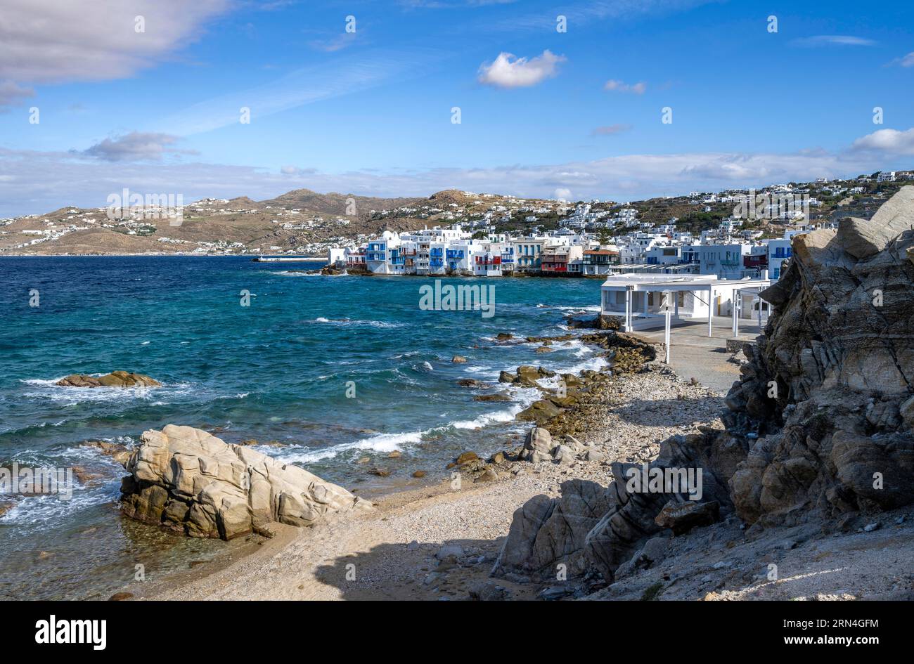 Beach with sand and rocks, white Cycladic houses in the back, Little ...