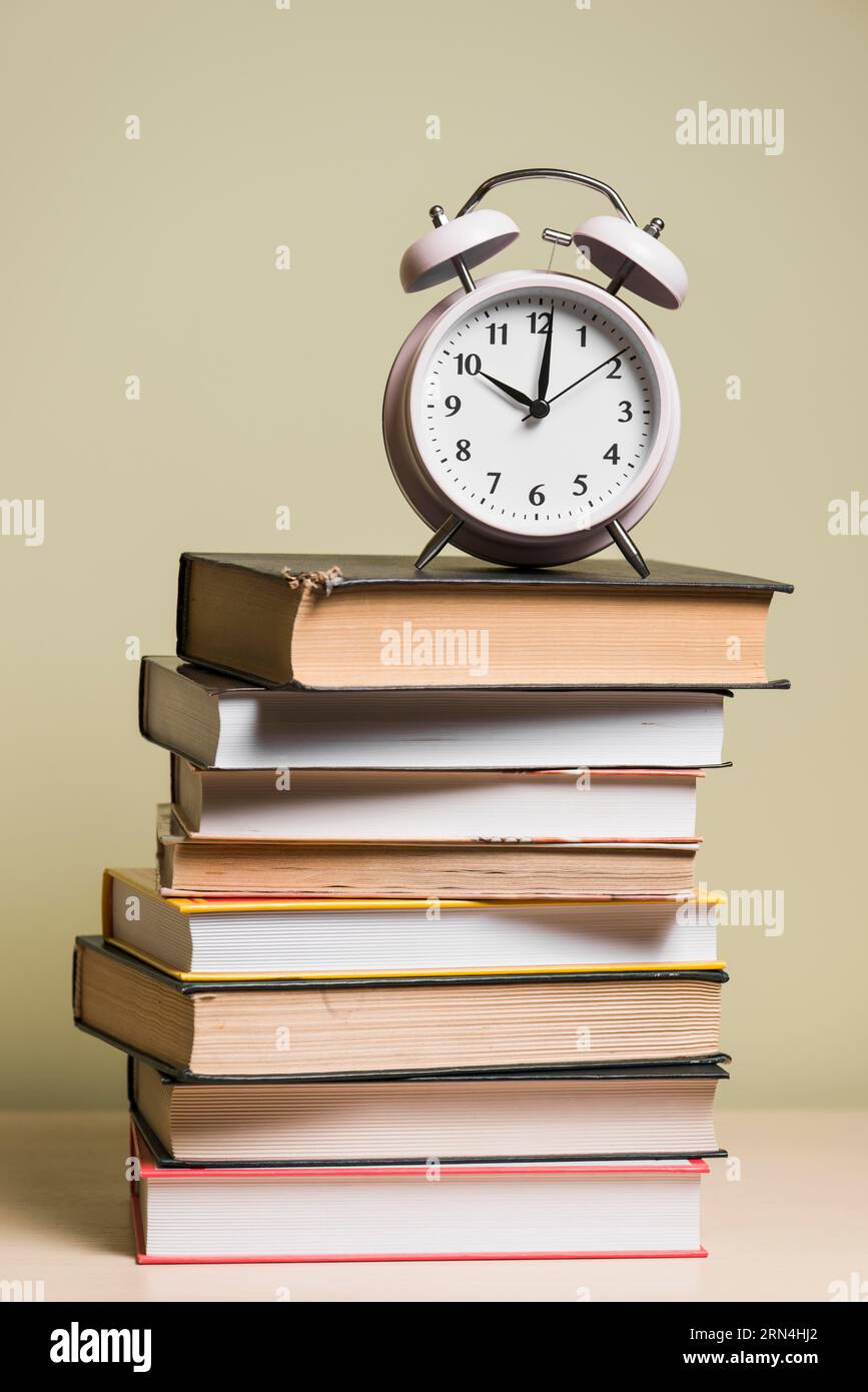 Alarm clock top stacked books wooden desk Stock Photo
