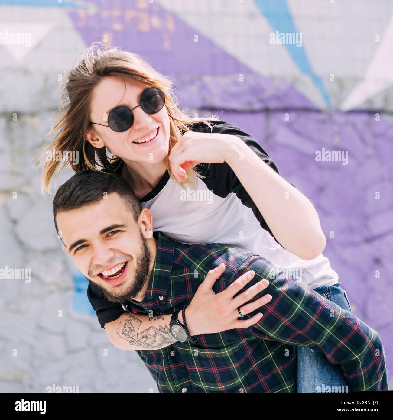 Handsome smiling young man taking her piggy ride his back Stock Photo