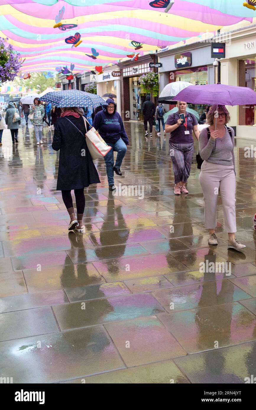 Rainy day in Bath. People with Umbrellas walk under the bannes which