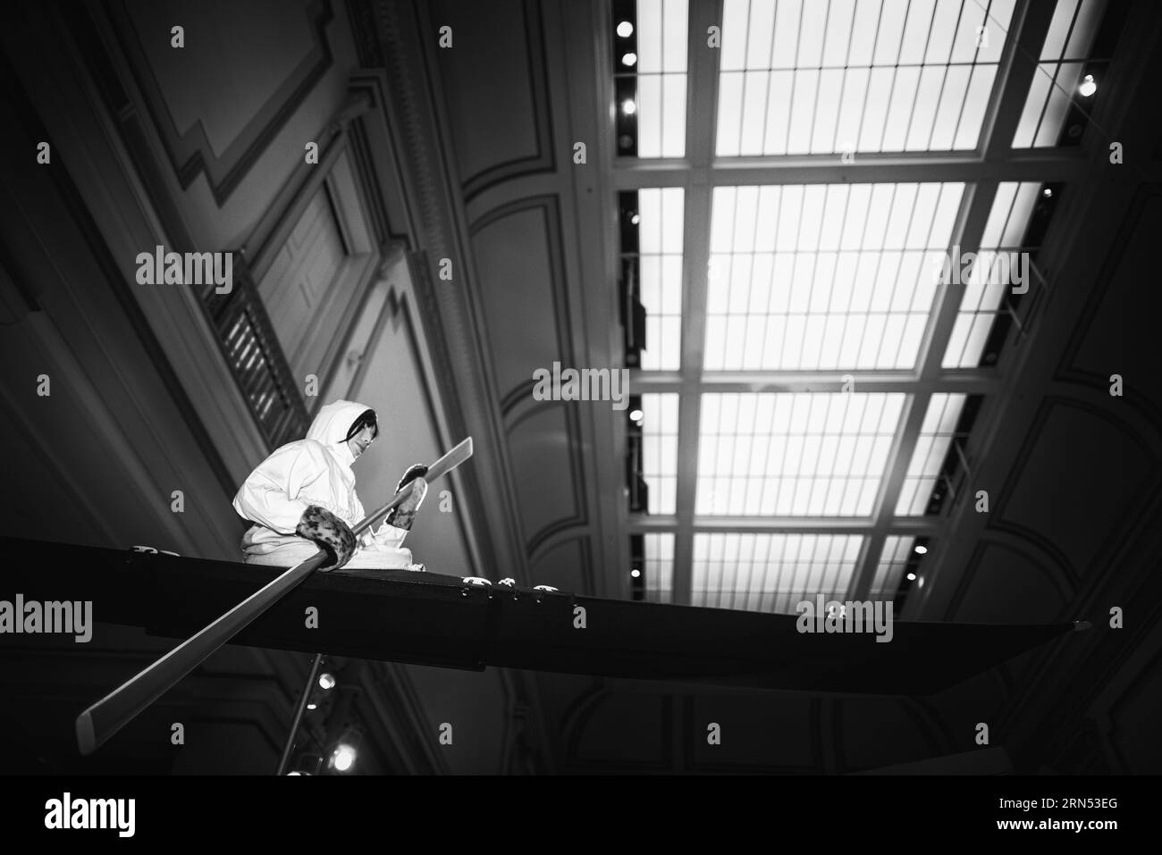 Eskimo in Boat exhibit, Smithsonian Natural History Museum, Washington, D.C. Black and white photograph of a person in a boat exhibit, viewed from a low angle, with a skylight in the background. Stock Photo