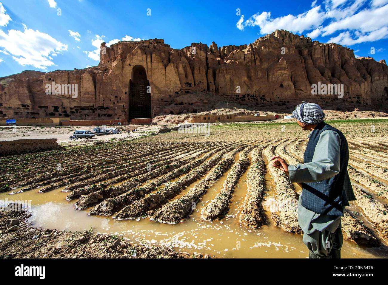 (150612) -- KABUL, June 12, 2015 -- A farmer works near the place where the Bamyan Buddha was located in Bamyan province, central Afghanistan, June 7, 2015. A Chinese couple, and Liang Hong, successfully projected the image of the tallest Buddha in Bamyan Valley on June 6 and 7, using the latest cultural relics-friendly technology, eliciting cheers from the local people. The two Bamyan Buddhas were bombed and smashed to the ground by Taliban in 2001 despite appeals from the international community. ) AFGHANISTAN-BAMYAN-BAMYAN BUDDHA-IMAGE PROJECTION ZhangxXinyu PUBLICATIONxNOTxINxCHN   150612 Stock Photo