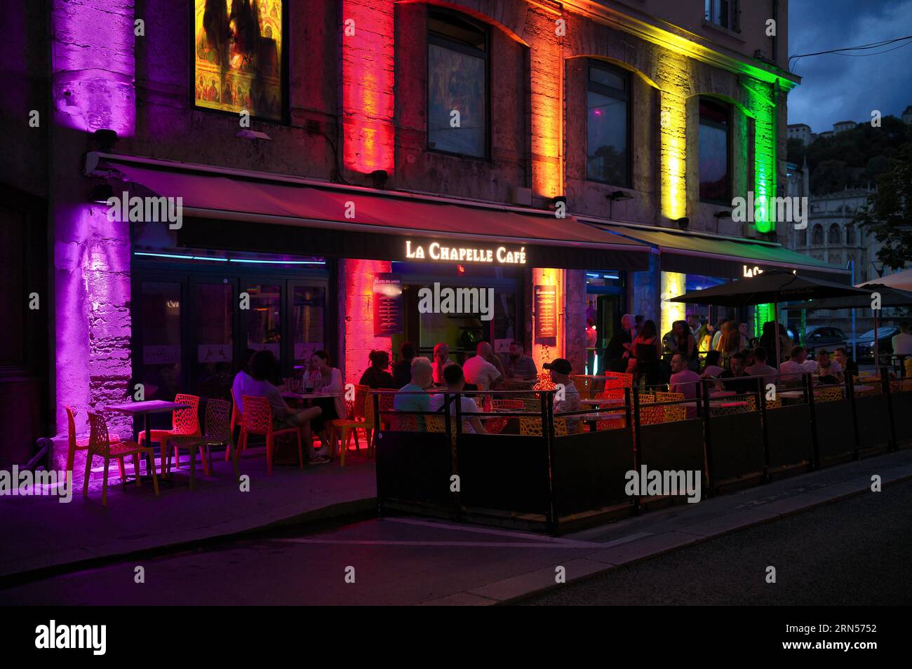 Night shot, people in bar, restaurant, street cafe La Chapelle Cafe. Neon light, Old Town, Lyon, Departement Rhone, Region Auvergne-Rhone-Alpes Stock Photo