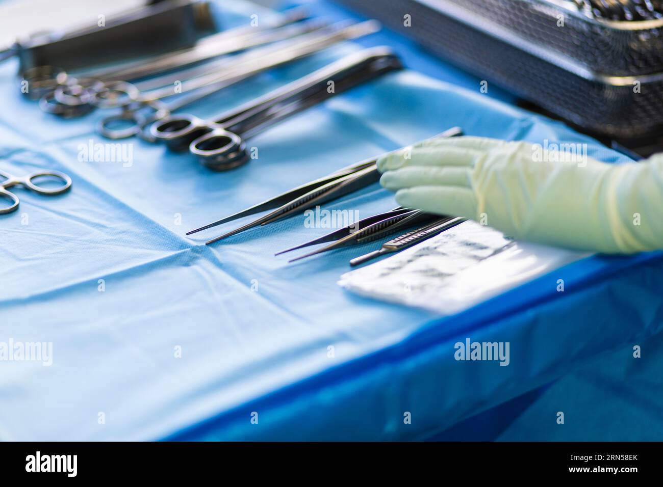 A hand reaches for a pair of tweezers in an operating theatre Stock Photo