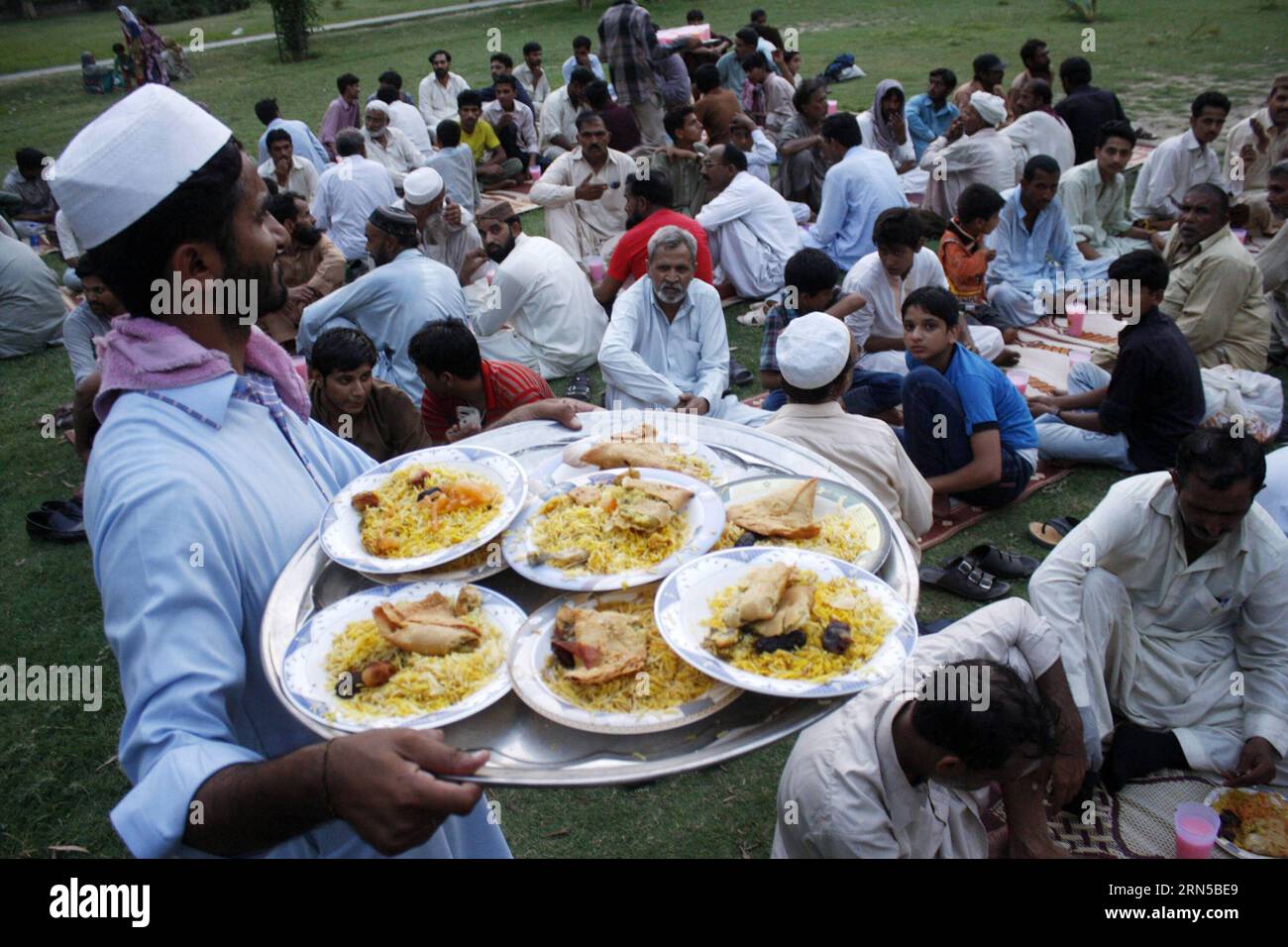 A man distributes Iftar food to Muslim devotees waiting to break their ...