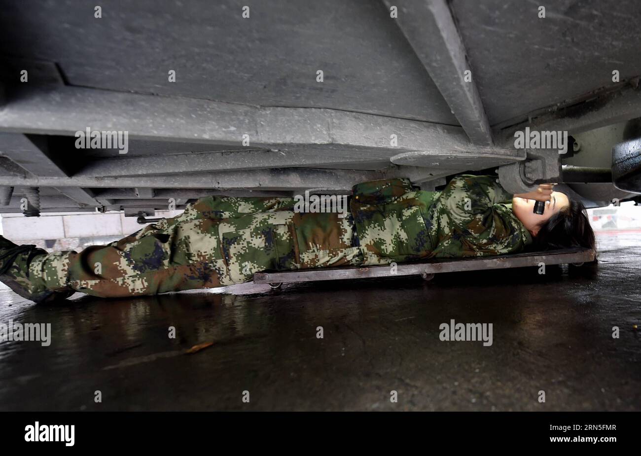 DEHONG, June 24, 2015 -- Zhang Liu checks the bottom of a car for contraband at the border checkpoint of Mukang in Dehong Dai-Jingpo Autonomous Prefecture, southwest China s Yunnan Province, June 24, 2015. Born in 1995, Zhang Liu became an anti-drug soldier in border checkpoint of Mukang in 2013. Grown up in an affluent family in central China s Hunan Province, Zhang said that being a soldier had always been her dream, which drove her to join the army after graduating from high school. Being a front line anti-drug force, the border checkpoint of Mukang has captured about 100 kilograms of drugs Stock Photo
