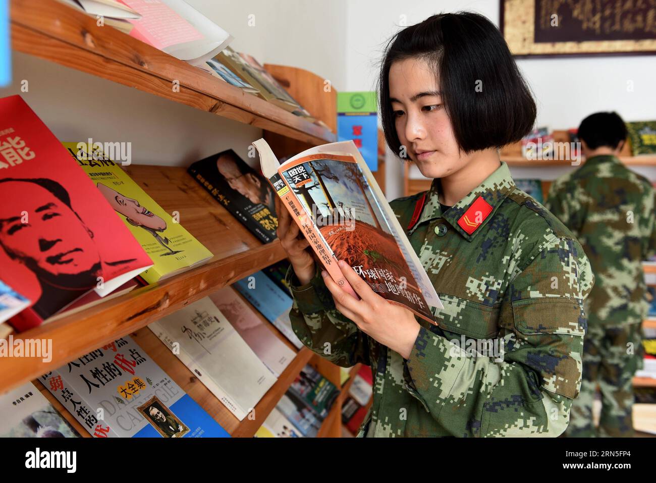 DEHONG, June 24, 2015 -- Zhang Liu reads at the cultural center of the border checkpoint of Mukang in Dehong Dai-Jingpo Autonomous Prefecture, southwest China s Yunnan Province, June 24, 2015. Born in 1995, Zhang Liu became an anti-drug soldier in border checkpoint of Mukang in 2013. Grown up in an affluent family in central China s Hunan Province, Zhang said that being a soldier had always been her dream, which drove her to join the army after graduating from high school. Being a front line anti-drug force, the border checkpoint of Mukang has captured about 100 kilograms of drugs since the be Stock Photo