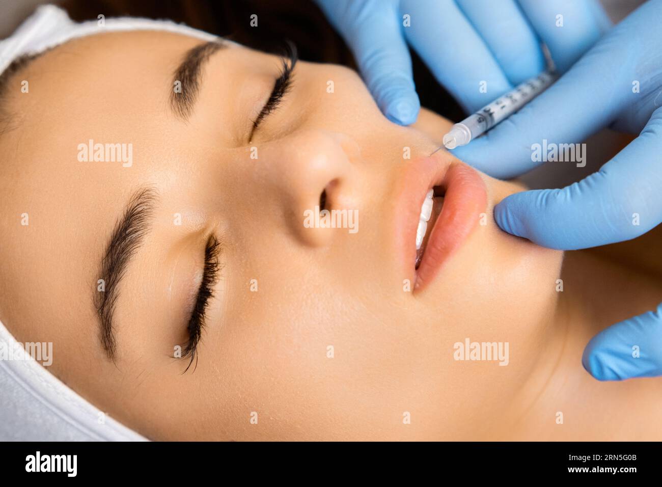 Young beautiful woman gets injection of botox in her lips for lip ...