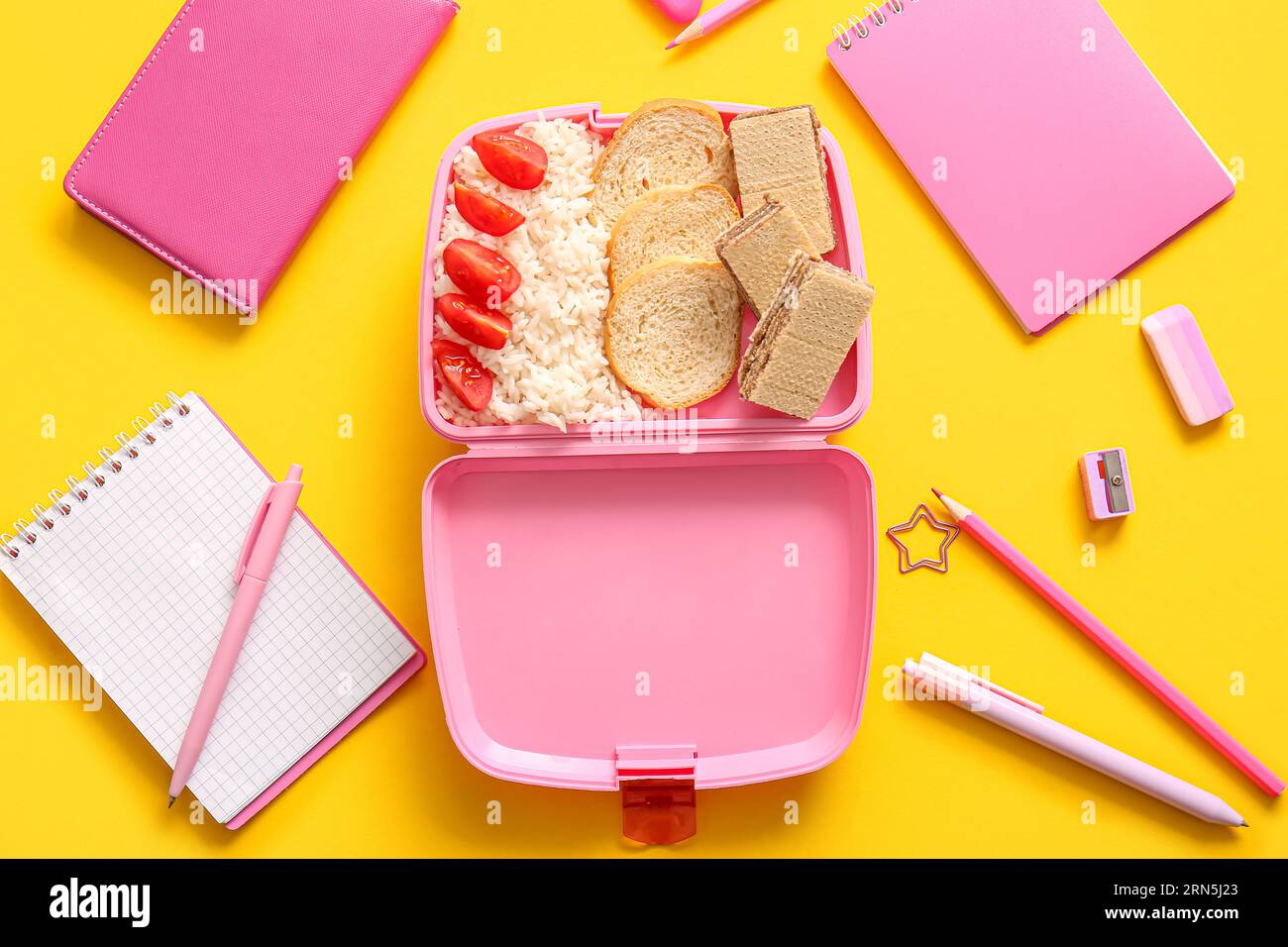Lunchbox with delicious food and different stationery on yellow background Stock Photo