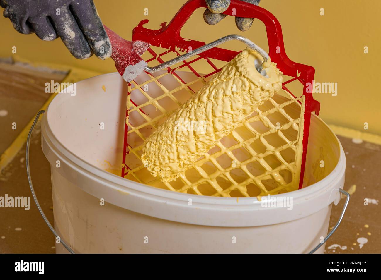 Paint roller on scraper grid in bucket with wall paint, painting work
