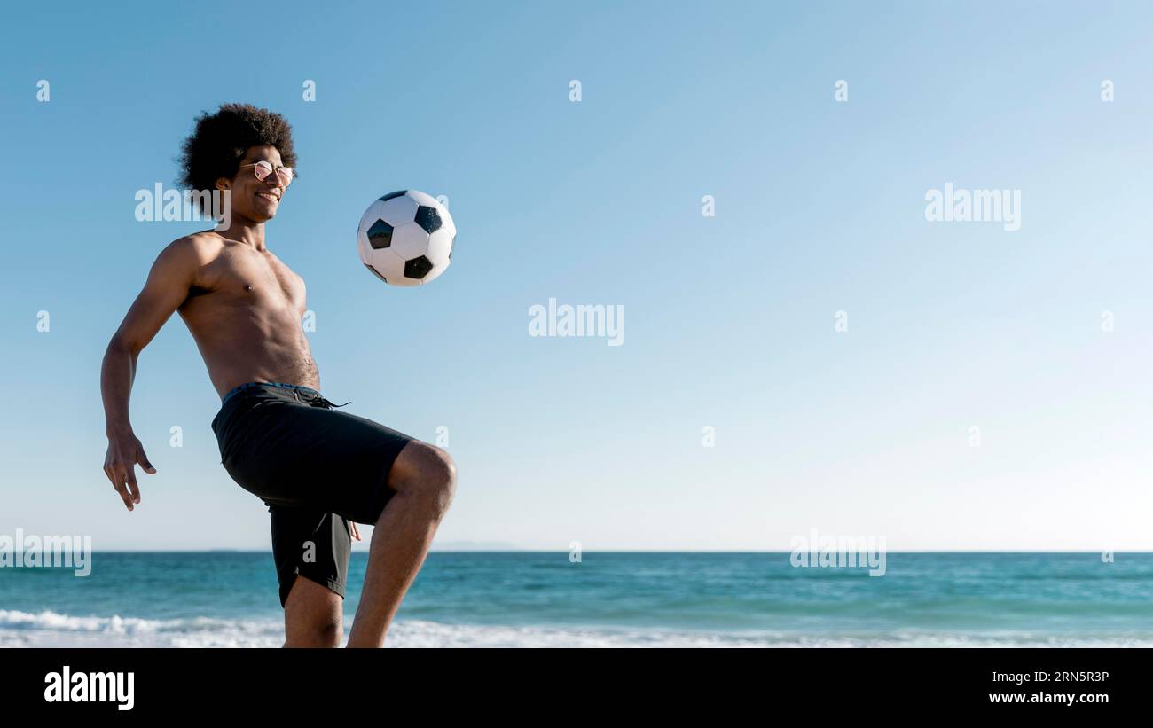 Excited young black male hitting ball seashore Stock Photo