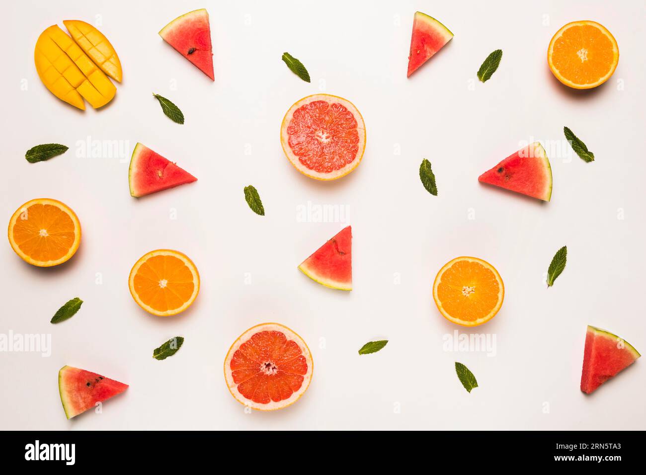 Sliced grapefruit watermelon orange mango green leaves Stock Photo