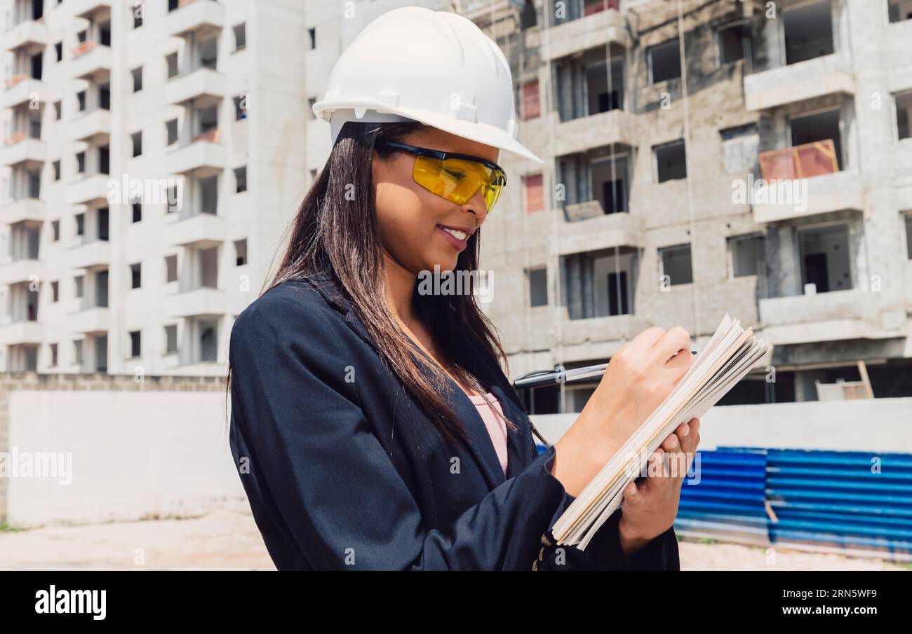 African american lady safety helmet with notepad near building construction Stock Photo