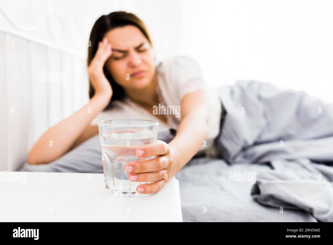 Female suffering from headache taking glass water Stock Photo