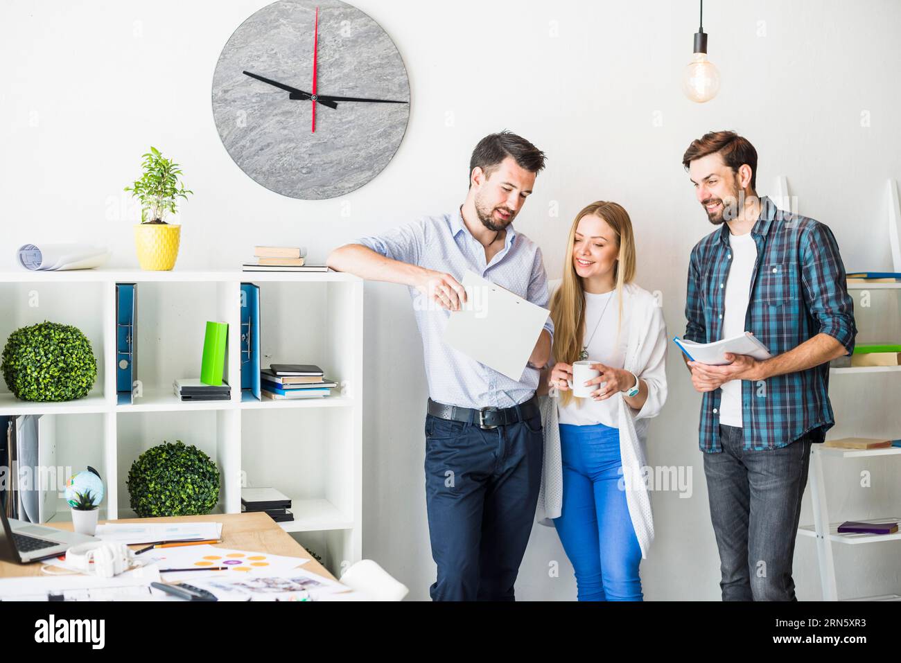 Group smiling young businesspeople looking document office Stock Photo ...