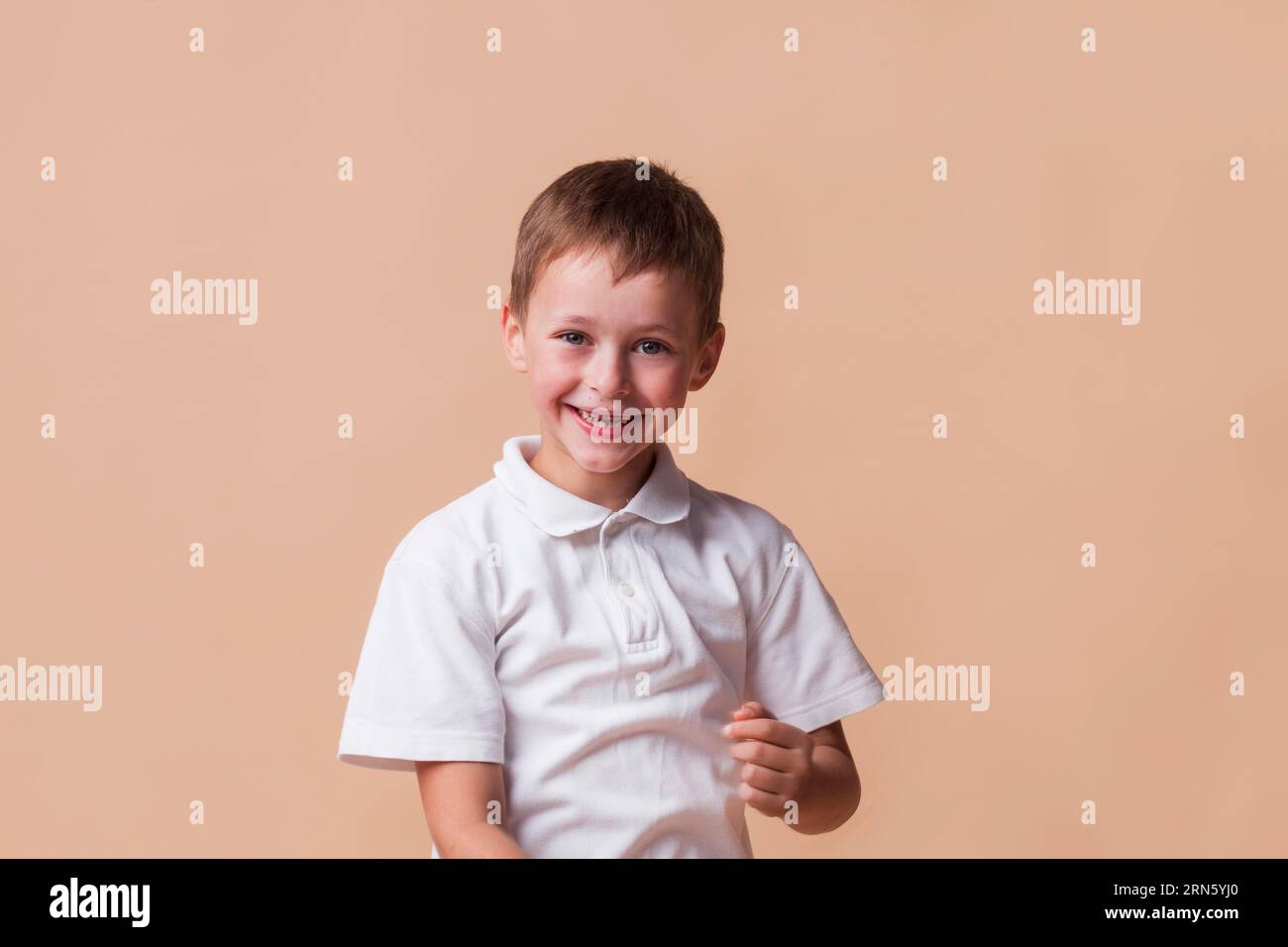 Smiling innocent boy beige backdrop Stock Photo