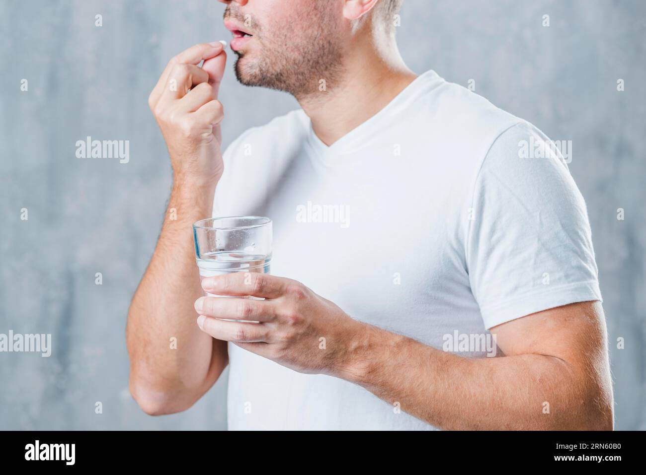https://c8.alamy.com/comp/2RN60B0/young-man-holding-glass-water-taking-medicine-2RN60B0.jpg