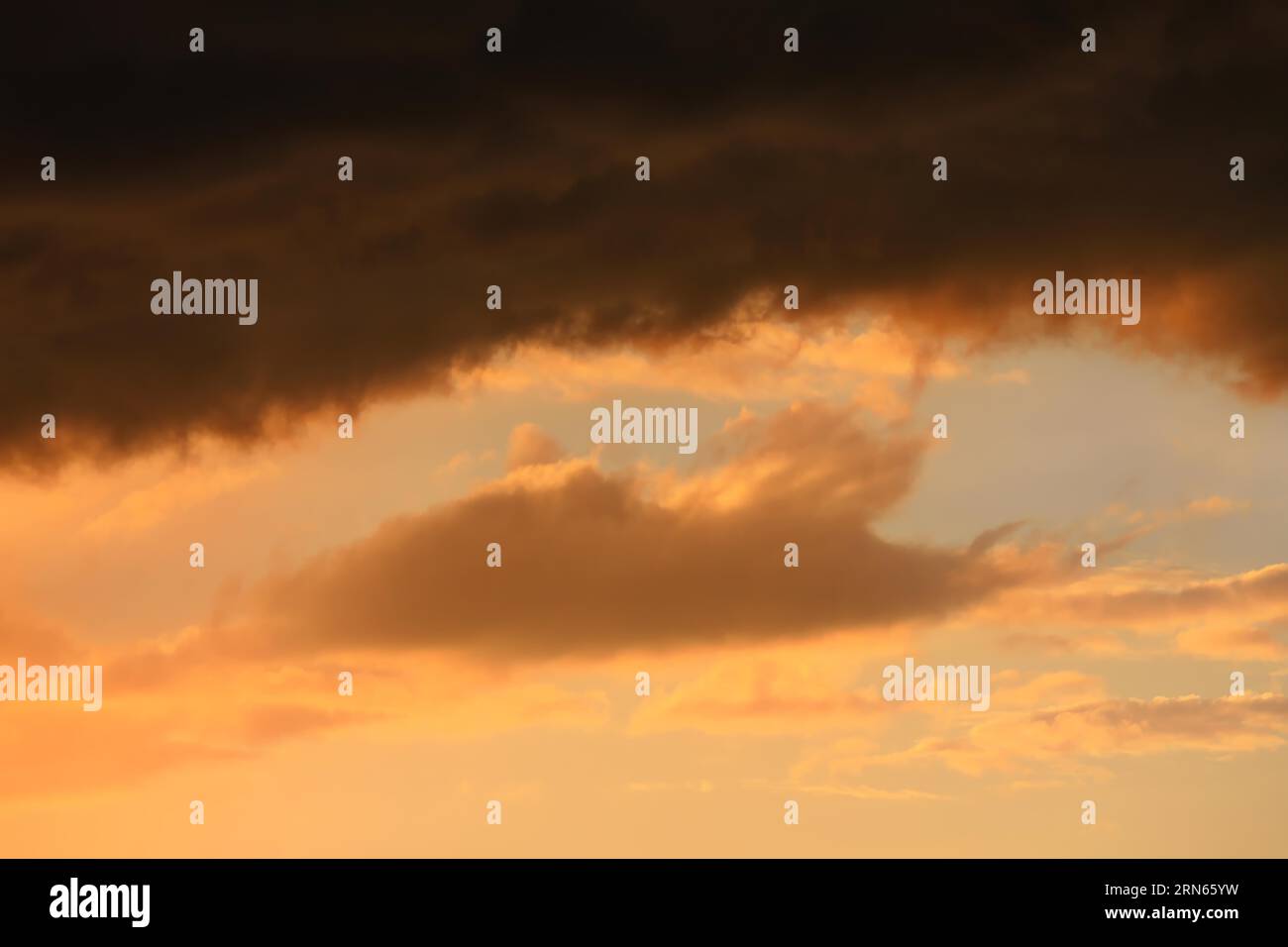 Cloudy sky at sunset. The sky is visible through a gap in the clouds. The image conveys a mood of an impending storm or bad weather Stock Photo