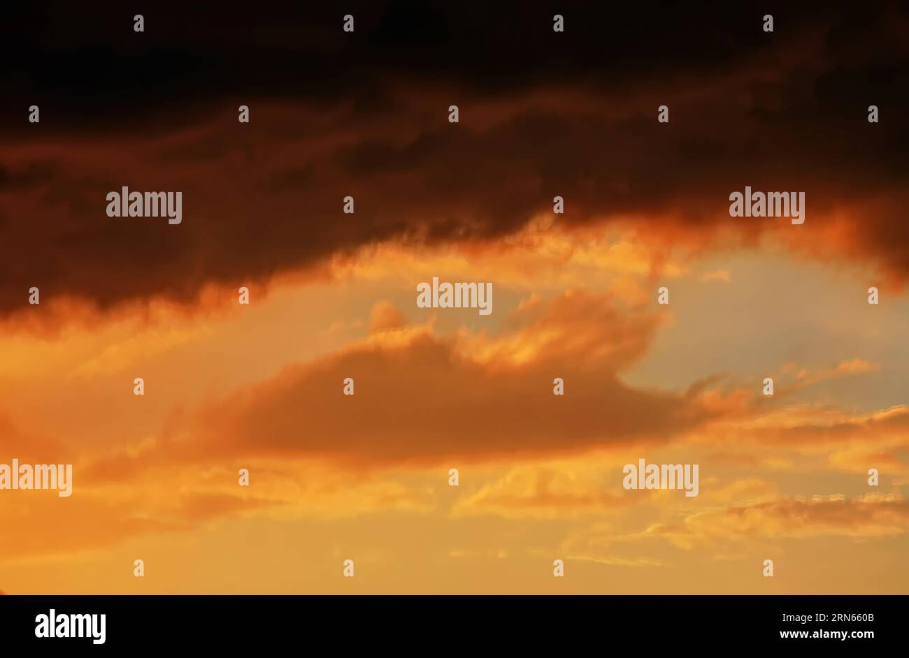 Cloudy sky at sunset. The sky is visible through a gap in the clouds. The image conveys a mood of an impending storm or bad weather Stock Photo