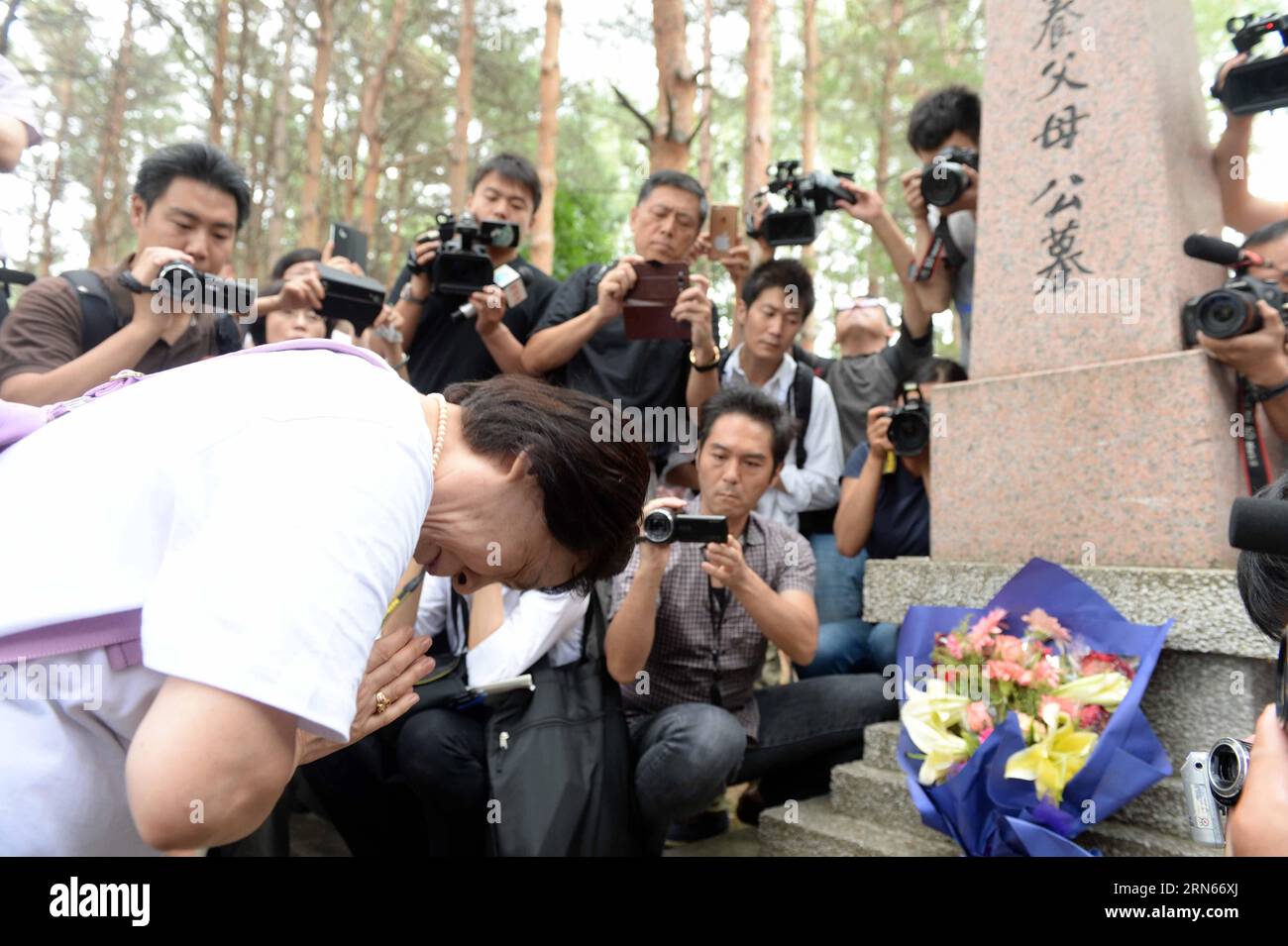 Ikeda Sumie, director general of a Tokyo support group for those Japanese returned from China, mourns for adoptive parents in front of a grave in a cemetery to memorize adoptive Chinese parents in Fangzheng County near Harbin, capital of northeast China s Heilongjiang Province, July 13, 2015. A group of 54 Japanese citizens, all now orphans, on Monday paid a visit to the graves of their adoptive Chinese parents here. Abandoned by their birth parents during the hasty retreat at the end of World War II in 1945, the orphans, now over 70 years old, were taken in and raised by the very Chinese resi Stock Photo
