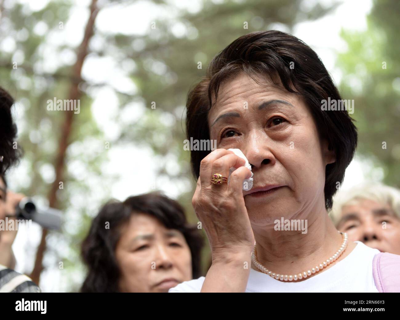 Ikeda Sumie, director general of a Tokyo support group for those Japanese returned from China, weeps in front of a grave in a cemetery to memorize adoptive Chinese parents in Fangzheng County near Harbin, capital of northeast China s Heilongjiang Province, July 13, 2015. A group of 54 Japanese citizens, all now orphans, on Monday paid a visit to the graves of their adoptive Chinese parents here. Abandoned by their birth parents during the hasty retreat at the end of World War II in 1945, the orphans, now over 70 years old, were taken in and raised by the very Chinese residents of those northea Stock Photo