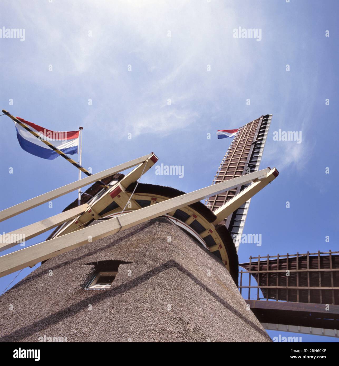 Classic Dutch windmill with two Dutch national flags seen from frog perspective Stock Photo